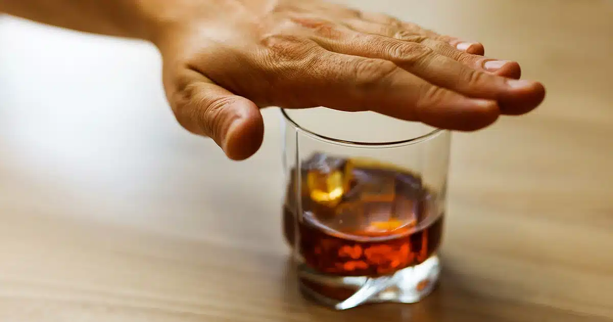 Hand covering a glass of alcohol