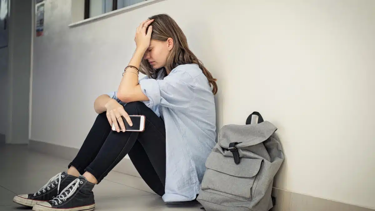 Person sitting on the floor with her head in her hand.